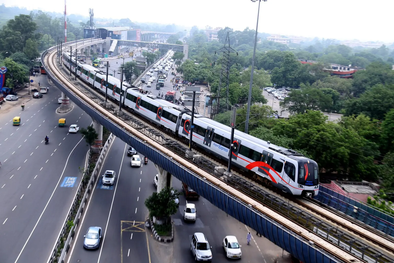 Airport Express train on the elevated section above a Delhi road.